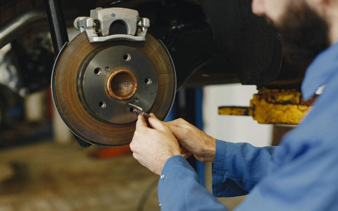 Technician inspecting brake pad and caliper during reno brake service